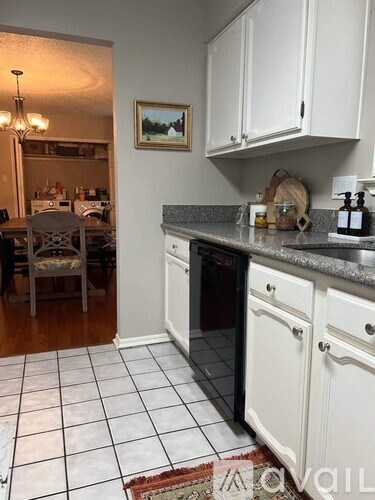 A kitchen with white cabinets and a black dishwasher.