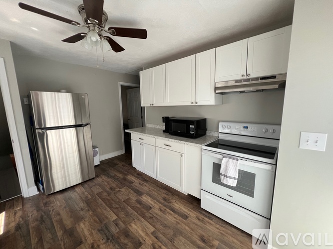 A kitchen with white cabinets and a wood floor.