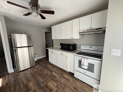 A kitchen with white cabinets and a wood floor.