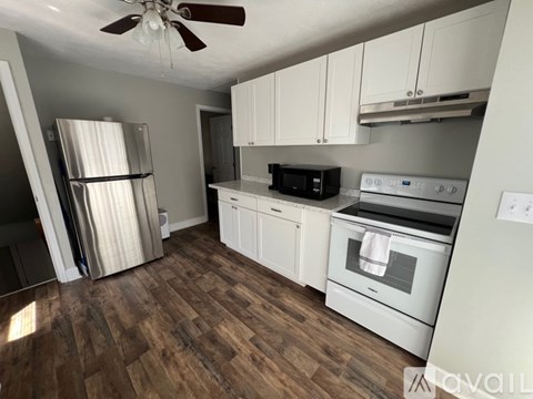 A kitchen with white cabinets and a wood floor.