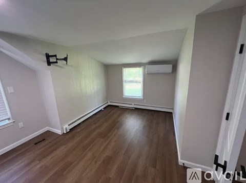 A room with wooden flooring and a window with blinds.
