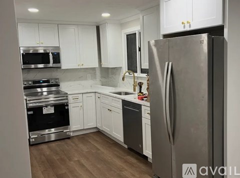 A modern kitchen with a stainless steel refrigerator, white cabinets, and a marble backsplash.