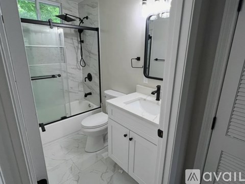 A white bathroom with a toilet, sink, and shower.