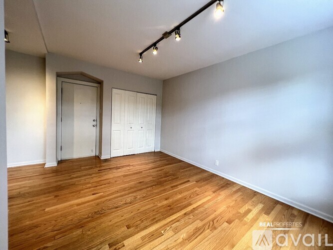 A room with wooden flooring and white walls, with a door and a cabinet.