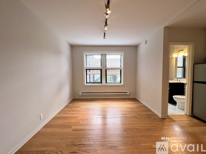 A spacious room with wooden floors and a window with blinds.