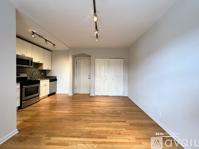 A spacious kitchen with wooden floors and white walls.