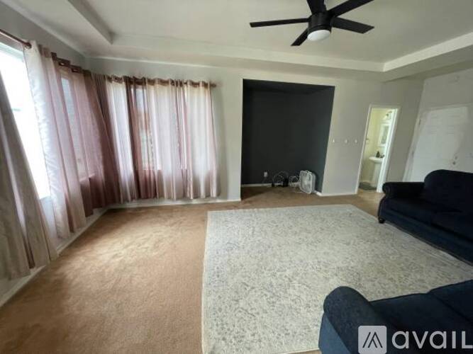A living room with a fan, a couch, and a rug.