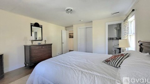 A bedroom with a large bed and a wooden dresser.