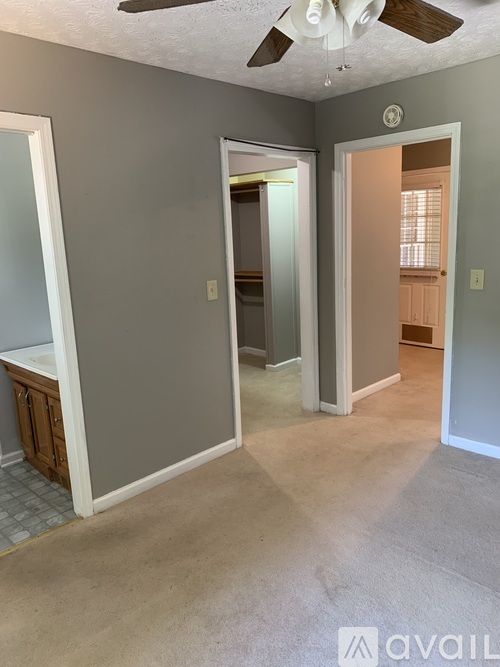 A room with a ceiling fan and a door leading to another room.