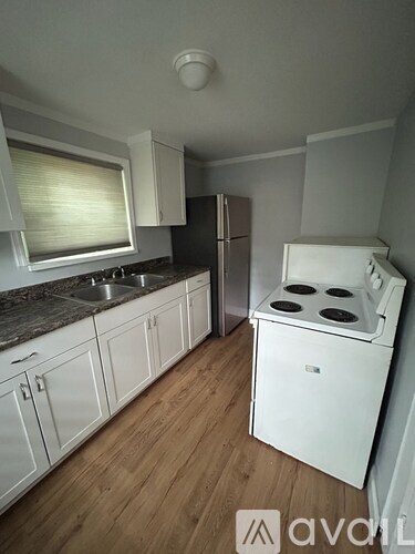 A kitchen with white cabinets and a white stove top oven.