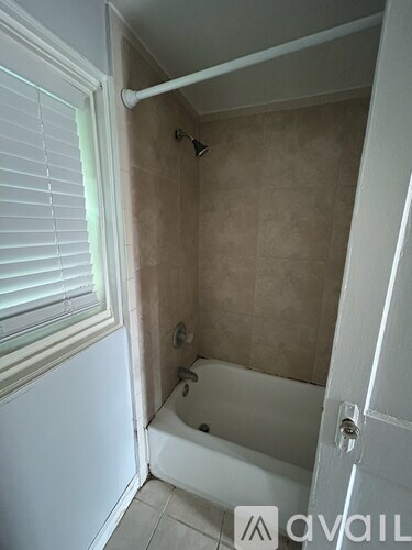 A small white bathroom with a tub and a window.