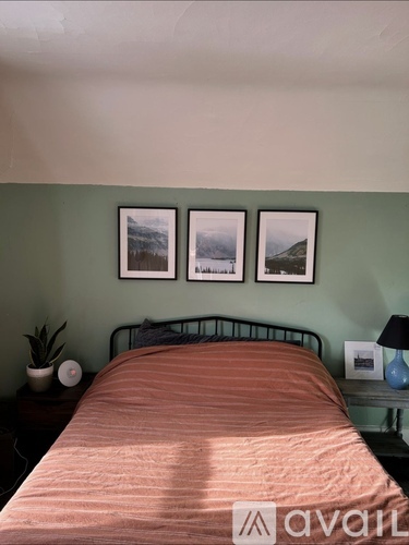 A bedroom with a bed, nightstands, and pictures on the wall.