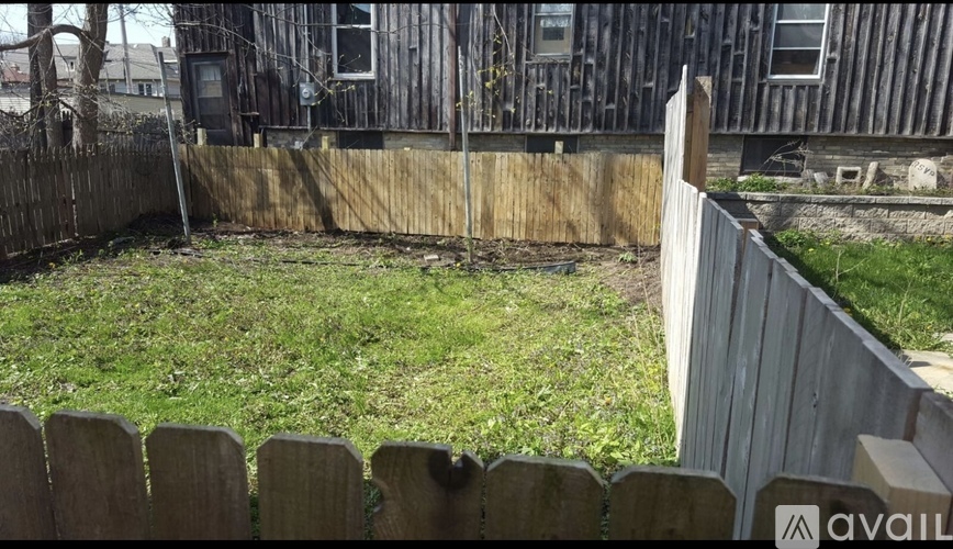 A backyard with a wooden fence and a grassy area.