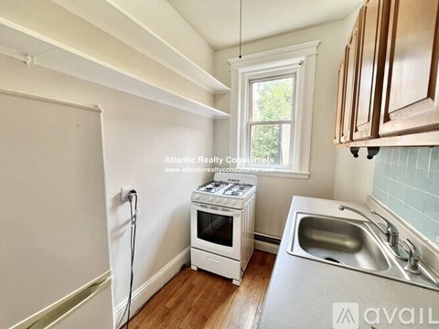 A kitchen with a sink, a window, and a refrigerator.