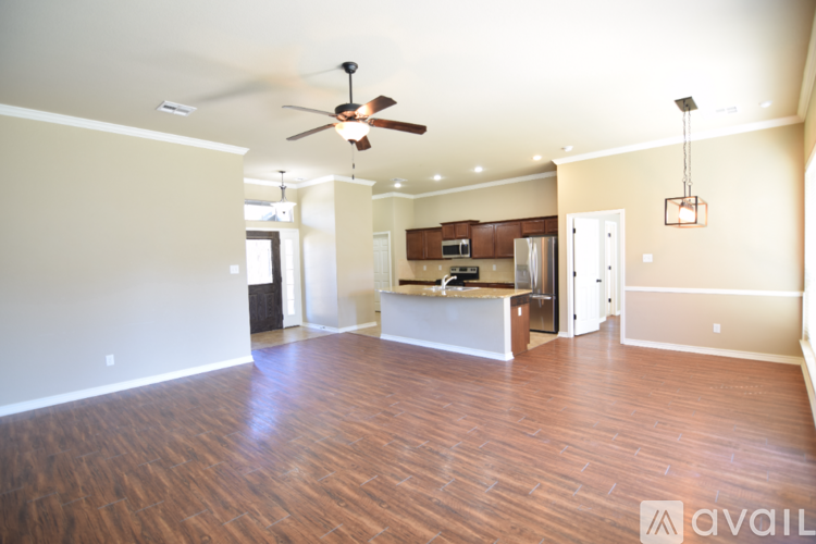 A spacious living room with hardwood floors and a ceiling fan.
