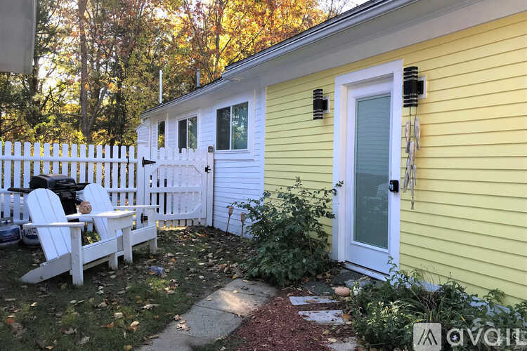 A yellow house with a white door and a white chair outside.