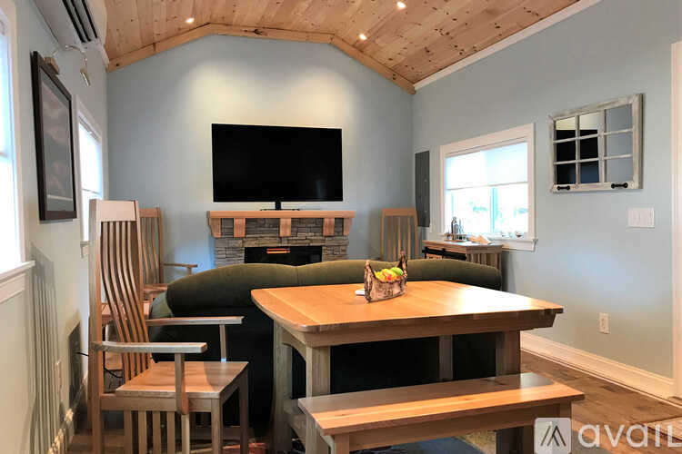 A wooden table with chairs and a television in a room with a wooden ceiling.
