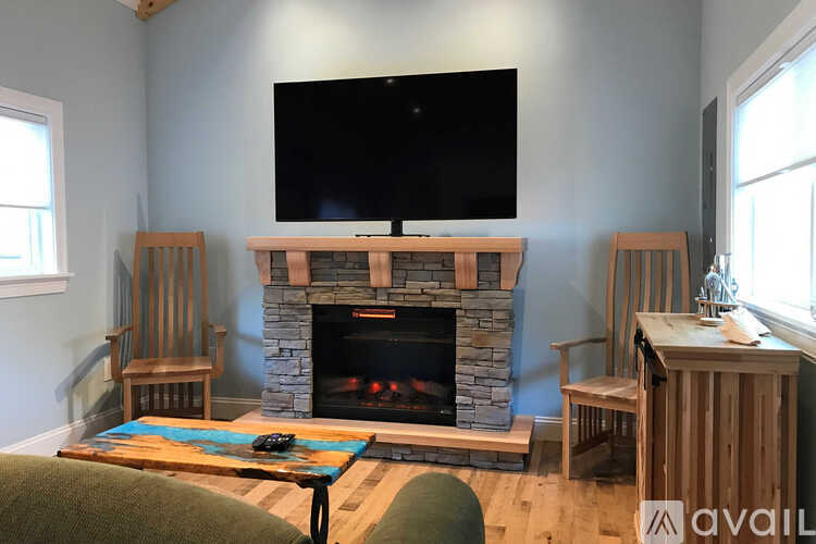 A living room with a stone fireplace and a flat screen TV mounted above it.