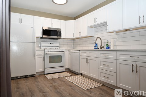A kitchen with white cabinets and a wooden floor.