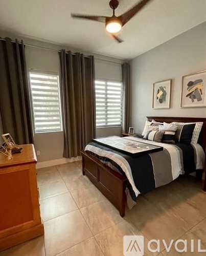 A bedroom with a bed, nightstand, and window with curtains.