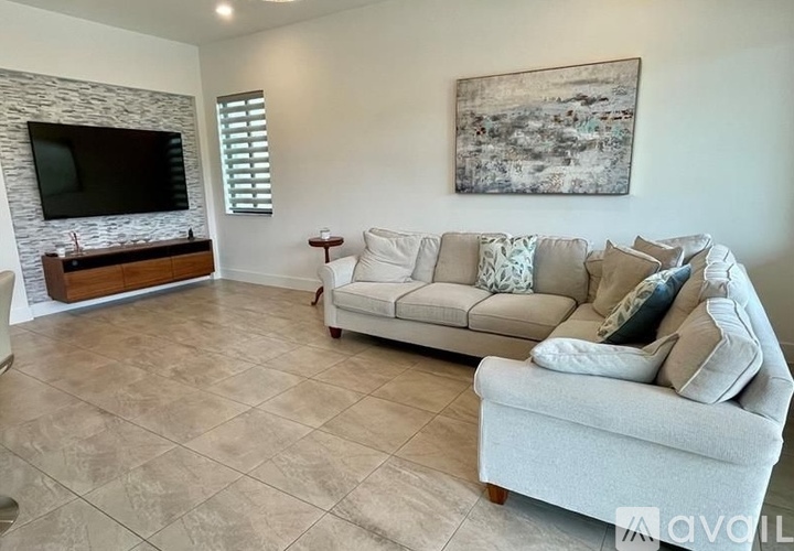 A living room with a couch, a television, and a painting on the wall.