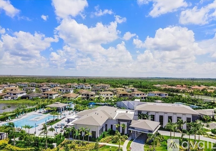 A large house with a pool in the foreground and a smaller house in the background.