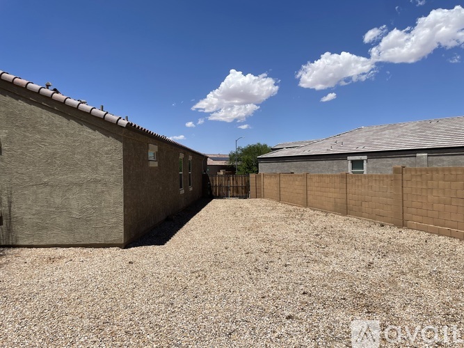 A gravel courtyard is surrounded by two buildings.
