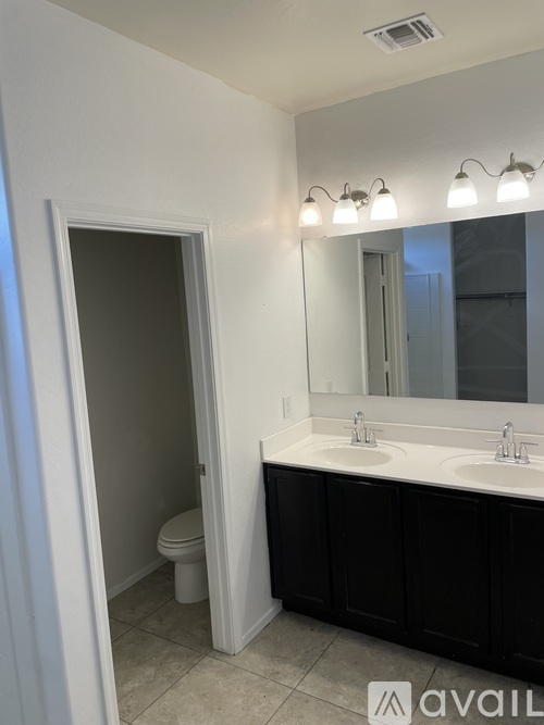 A bathroom with a toilet, sink, and mirror.