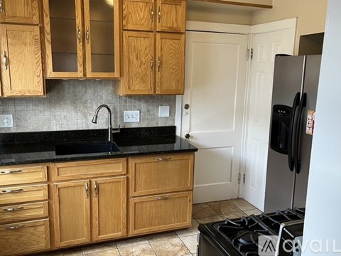 A kitchen with wooden cabinets and a black countertop.