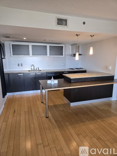 A kitchen with a wooden floor and a table in the middle.