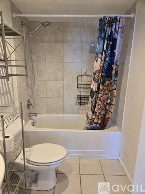 A white toilet sits in a bathroom next to a bathtub.