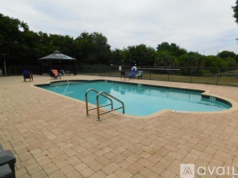 A pool with a brown tile floor and a black fence.