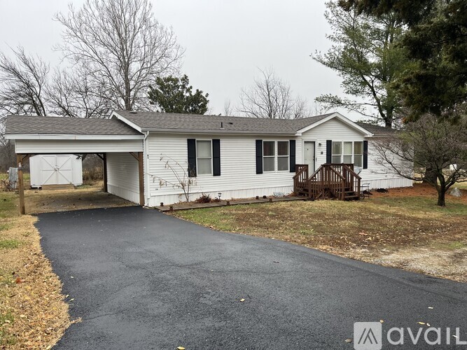 A white house with a black roof and a driveway in front.