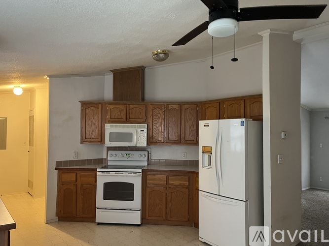A kitchen with white appliances and wooden cabinets.