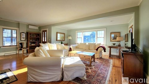 A living room with a white couch and a rug.