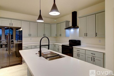 A kitchen with a white counter top and a black faucet.