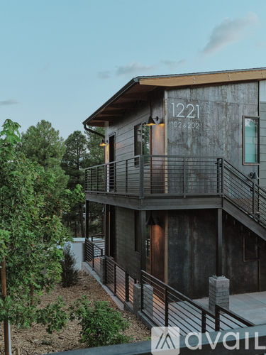 A modern house with a balcony and a staircase leading to the entrance.