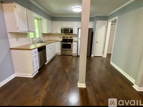 A kitchen with white cabinets and a wooden floor.