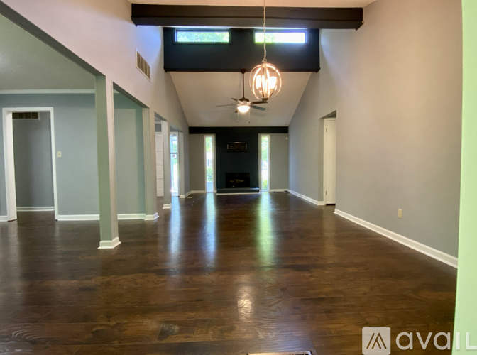 A spacious room with wooden floors and a light hanging from the ceiling.