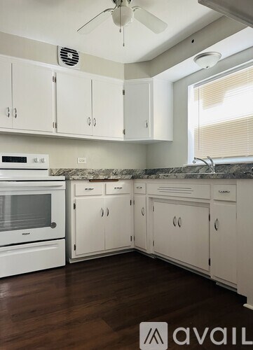 A kitchen with white cabinets and a marble countertop.