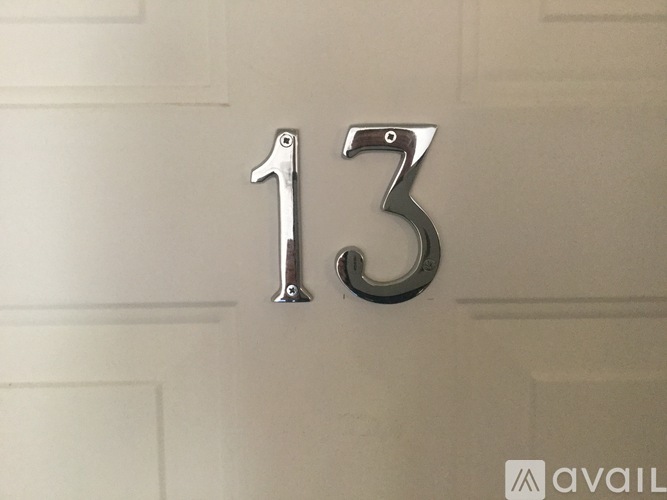 A metallic number 13 is mounted on a white door.