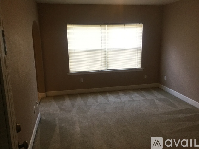 A room with a carpeted floor and a window with blinds.