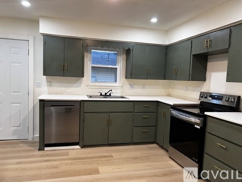 A kitchen with dark green cabinets and stainless steel appliances.