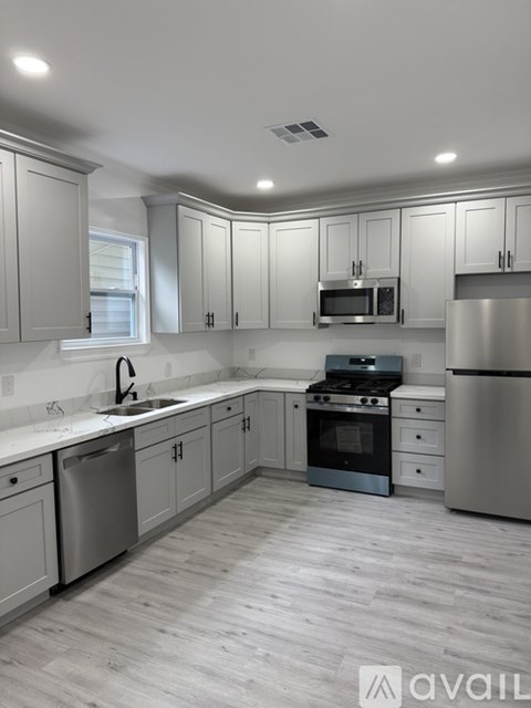 A modern kitchen with stainless steel appliances and wooden flooring.