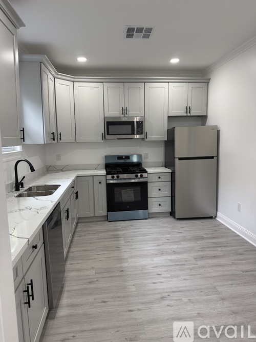 A kitchen with white cabinets and a wooden floor.