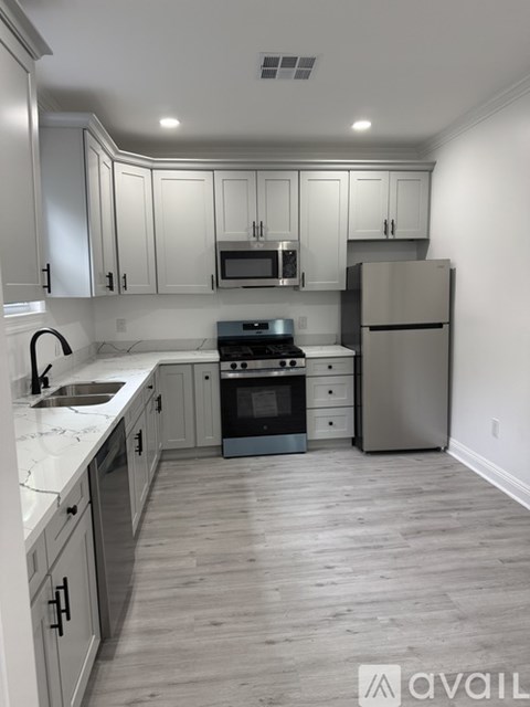 A kitchen with white cabinets and a wooden floor.