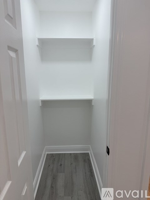 A hallway with a wooden floor and white walls.