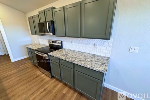 A kitchen with green cabinets and a granite countertop.