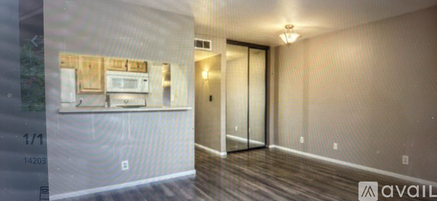 A hallway with a door on the right and a kitchen area on the left.