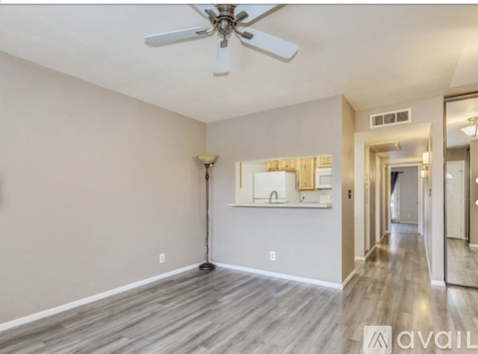 A spacious room with a ceiling fan and a long hallway leading to another room.